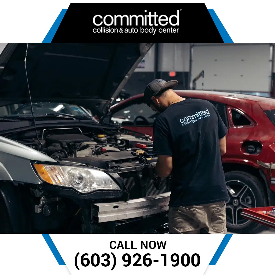 Local Auto Body Shop vs. Chain: Which Repairs Your Car Faster? 2 An auto body technician in a branded t-shirt leaning over an open hood to perform front-end collision repairs on a silver car.